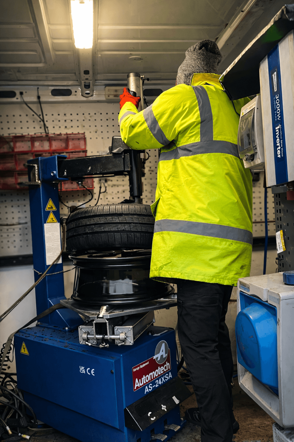 Emergency roadside tyre change being performed on a dark motorway hard shoulder